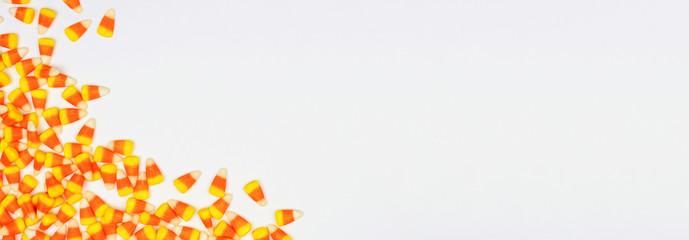 Halloween candy corn corner border banner. Top view on a white background with copy space.