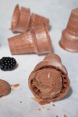 Coffee chocolate ice cream with black waffle cups with blackberries, on a light background
