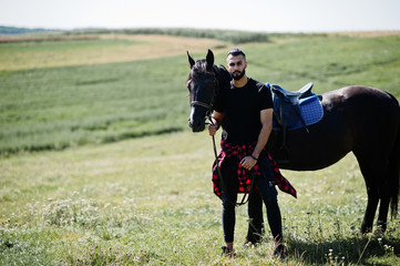 Arab tall beard man wear in black with arabian horse.