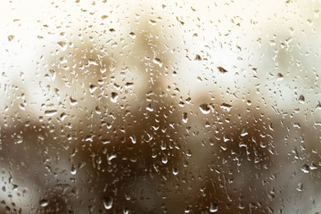 Fototapeta na wymiar Close-up orange rain drops on the glass, rainy season in autumn.