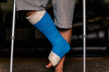 Male stood on 1 foot with crutches supportiing weight and stability At home