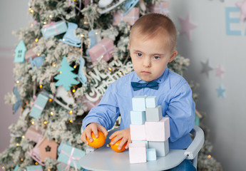 A little boy with Down syndrome builds a tower of blocks, a child with a genetic disease, disabled...
