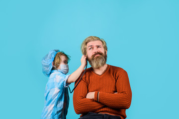 Doctor game. Kid play doctor with dad. Medicine game. Boy doctor playing with dad. Treatment. Home treatment. Kid in doctor mask. Emergency.