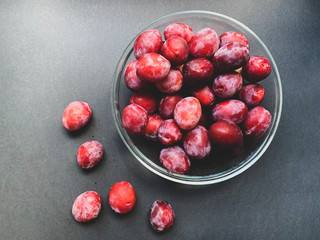 Fresh plums with a glass plate on a black background. Proper nutrition, vegetarianism, health benefits, vitamins, diet.