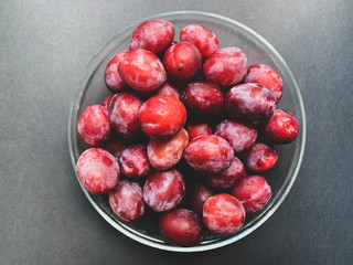Fresh plums with a glass plate on a black background. Proper nutrition, vegetarianism, health benefits, vitamins, diet. 