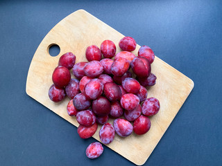 Fresh plums with a wooden Board on a black background. Proper nutrition, vegetarianism, health benefits, vitamins, diet.