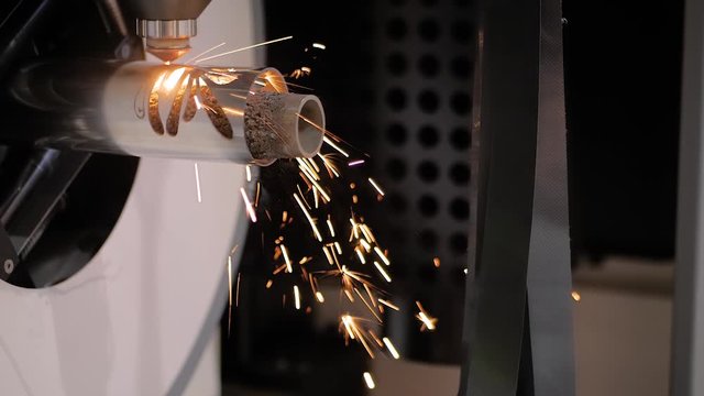 Slow motion: automatic cnc laser cutting machine working with metal workpiece with sparks at factory, plant. Metalworking, machining, industrial, equipment, technology, manufacturing concept