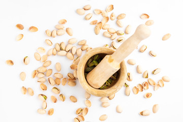 Peeled pistachios in mortar on a white background