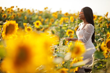 Pretty young black woman wear summer dress pose in a sunflower field.