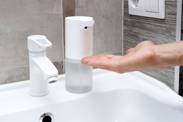 Close up of a man using automatic contactless soap dispenser