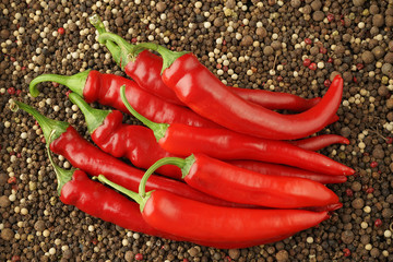 beautiful ripe large red hot chili with a green tail on a dark background consisting of balls of...