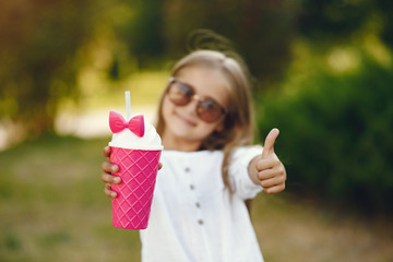 Cute little girl in a park. Child in a white blouse. Lady with a pink cup.