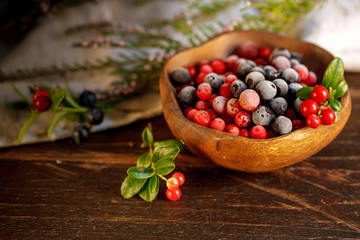 frozen cranberries and blueberries in a wooden bowl, decorated with a sprig of fresh cranberries....