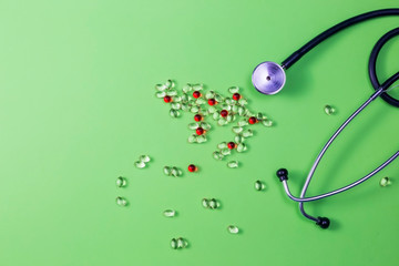 Pills, stethoscope and medical masks on green background.