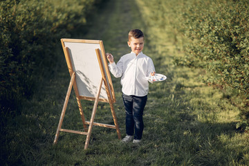 Little boy in a summer park. Cute child drawing