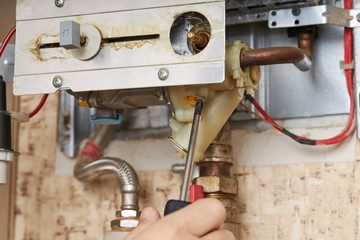 service technician repairing gas water heater indoors. water heater maintenance. diy concept