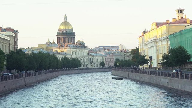 Saint Isaac's Cathedral golden dome behind Moyka river, Saint Petersburg, Russia. Media. Beautiful view of the city street with many historic buildings, concept of architecture.
