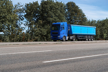 Fototapeta na wymiar truck on the road, side view, empty space on a blue container - concept of cargo transportation, trucking industry