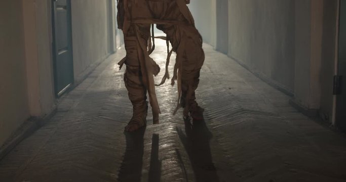Scary Egyptian mummy creeping down hallway in abandoned cursed house. Creepy ancient zombie walking with clumsy moves - halloween costume 4k footage