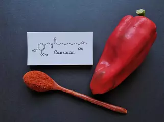 Fotobehang Structural chemical formula of capsaicin molecule with fresh red chili peppers and chili powder in wooden spoon. Capsaicin is the compound found in chili peppers that gives them their hot, spicy kick. © Danijela