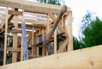 an ax stuck into a wooden beam, construction of a wooden house.