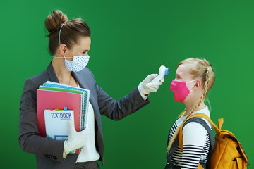 modern female teacher and pupil measures temperature - Powered by Adobe