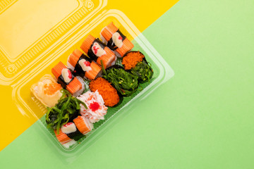 Japanese food (sushi) in clear plastic food box on yellow background