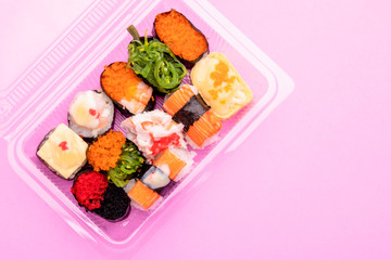 Japanese food (sushi) in clear plastic food box on pink background