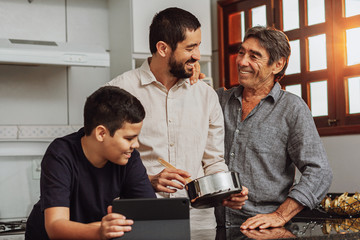 Male members of three generation family enjoying the day together in home cooking in the kitchen
