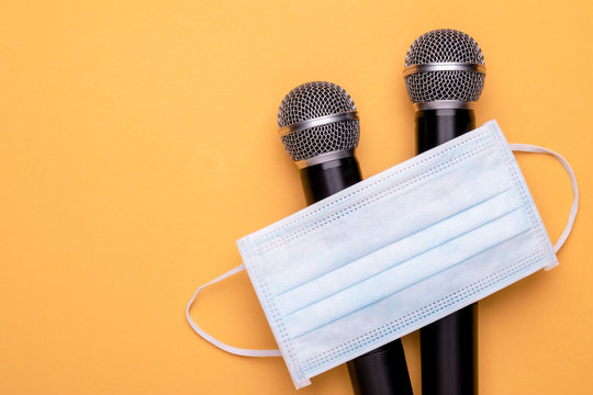 Keep wearing mask while speak. Top view new preventive face mak and black wireless microphone on color background. Copy space for text or design