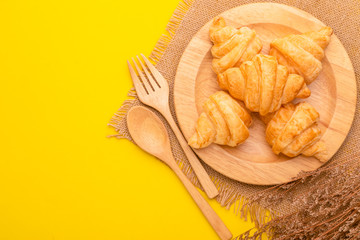 Mini Croissant in wooden dish on yellow background. Food concept with copy space
