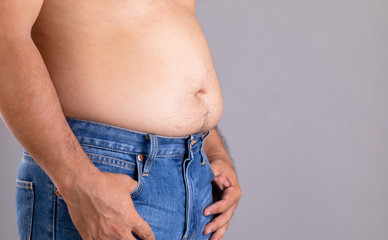 Fat man standing and show his tummy studio shot on grey background with copy space for text or...