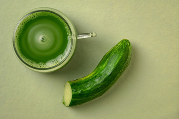 a glass cup of fresh home made green cucumber juice on a paper background with a copy space, healthy eating concept