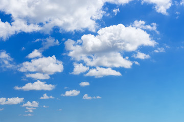 White fluffy clouds floating slowly high in the bright blue summer sky on a day. Nice sunny weather, seaside vacations and summer holidays. Scenic skyscape.