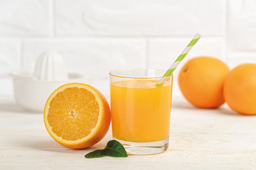 Glass of freshly squeezed orange juice with a paper drinking straw and half an orange on a white wooden table. Vegetarian, raw food diet and healthy eating. Organic antioxidant.