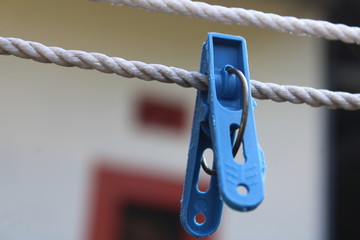 Close-up of a blue wet peg hanging on a blue wire in the sunlight