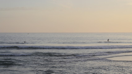 Calm water, people surfing, sunset beach in Paraty, Rio de Janeiro - Brazil.