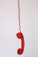 Red vintage cable telephone hanging over white background