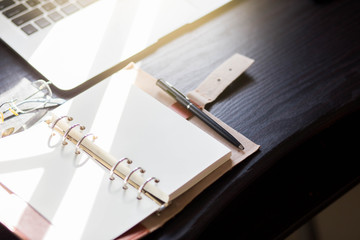 notebook and pen on wooden desk with laptop.