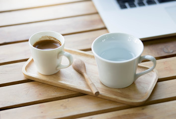 cup of coffee on wooden table with laptop.