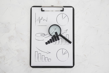 business analysis and statistics, desk with mixed graphs and charts on clipboard with magnifying...
