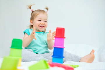 Happy toddler claps his hands playing with toys.
