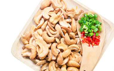 Tasty cashew nuts with red chilli in wooden plate.