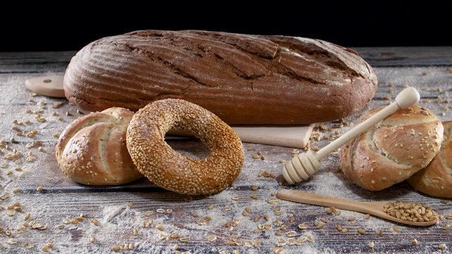 Loaf of fresh organic rye bread and healthy bakery products on the table with flour and grains 