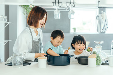新築のリビングで母親が子供二人に料理を教えている　fmaily kids 子育て