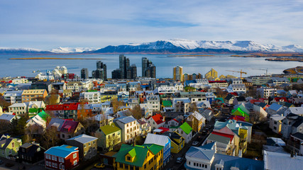 Aerial view of colorful buildings in Reykjavik Iceland with mountains and clouds in the background - obrazy, fototapety, plakaty