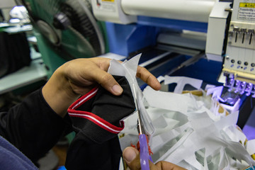 Female worker hand cutting lining paper on staff uniform on Garment Manufacturers at Kota Kinabalu, Sabah, Malaysia