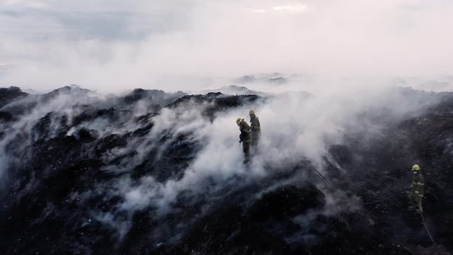 Aerial view away from firefighters extinguishing a wildfire, smoke rising in burnt nature, in the Amazon jungle, Brazil, South America	-  pull back, drone shot
