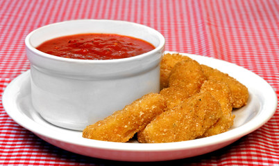 Mozzarella sticks and a bowl of marinara sauce.