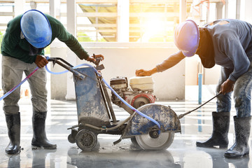 Workers using cutting machine are cutting concrete for expansion and isolation joint of slab on...